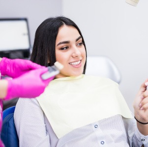 Dental patient holding mirror, admiring her smile