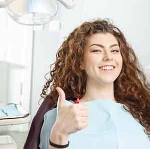 Woman giving a thumbs up in dental chair