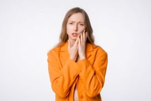 Frowning woman touching the side of her face 