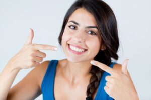 Smiling young woman pointing at her perfect teeth