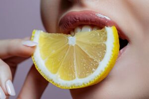 Woman holding a lemon slice close to her mouth