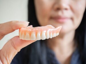 Woman holding denture between two fingers